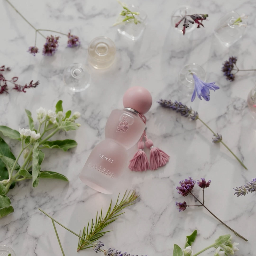 Perfum Sense Laverne ułożony na marmurowej powierzchni z kwiatami – elegancki, kwiatowo-piżmowy zapach dla kobiet